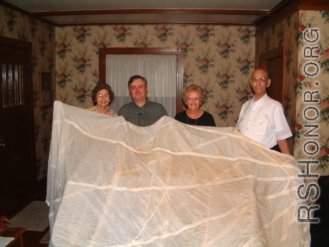 Family members holding silk parachute from Price's first bailout.