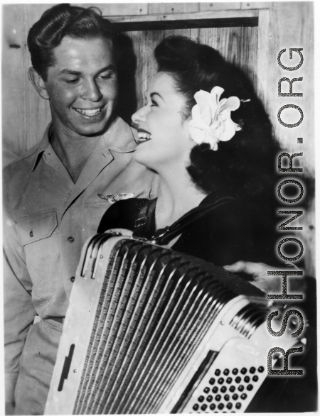 Celebrities visit and perform at Yangkai, Yunnan province, during WWII: Ruth Dennis poses with the accordion and a happy GI.