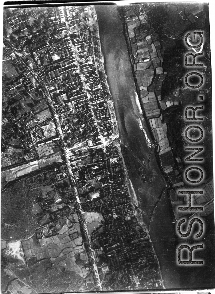 Bombing of small riverside town likely in SW China (esp. Guangxi), but possibly in Burma, or French Indochina. During WWII. Signs of previous bombings are visible about, including destroyed houses along the main road, and bomb craters here and there.