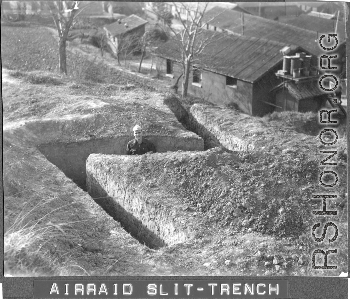 Flyer in air raid slit trench at Chanyi (Zhanyi), during WWII. Barracks behind.