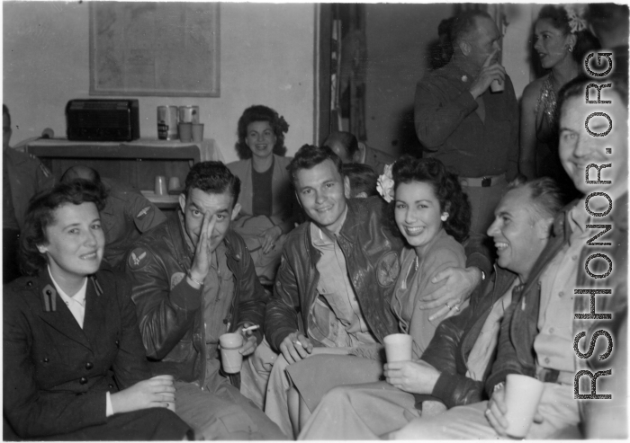 Celebrities visit and perform at Yangkai, Yunnan province, during WWII: GIs and medical staff share a meal with celebrities, including Betty Yeaton seated, Jinx Falkenburg standing in right background, and a Hollywood movie star on far left, and Mary Landa seated against back wall.