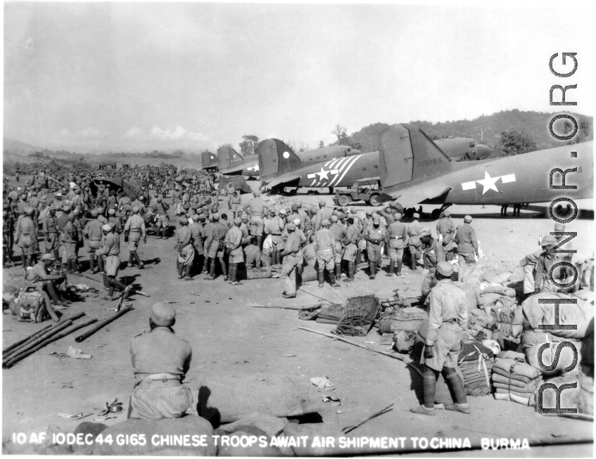 Chinese troops in Burma await transport on C-47 to China. Note the row of C-47 transport planes waiting. December 10, 1944.