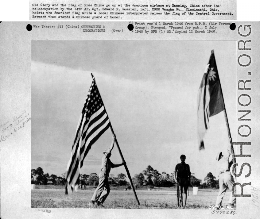 Flag raising ceremony at Nanning Air Base, China, on 8 July 1945, after its re-occupation by the Allies. Sgt. Edward F. Rossler hoists American flag, while a Chinese interpreter raises Chinese Nationalist flag.