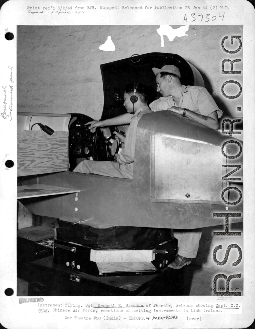 Instrument flying training. Sgt. Kenneth E. Brandon showing Capt. C. C. Wang, Chinese Air force, reactions of setting instruments in link trainer. India.