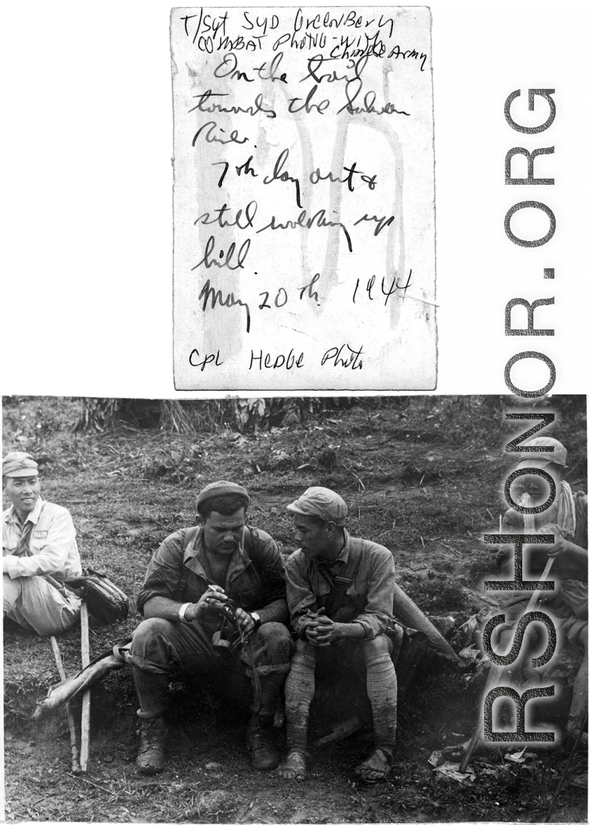 T/Sgt. Syd Greenberg, Combat Photographer, interacts with a Chinese soldier on the trail towards the Salween River. "7th day out and still walking up hill."  May 20, 1944.  Photo by Cpl. Hedge.