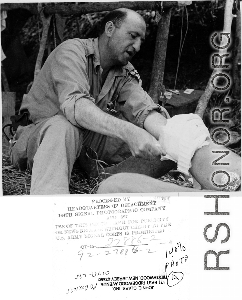 An American doctor treats a leg injury in on site in the forest in the CBI during WWII.  Photo from John E. Clark.