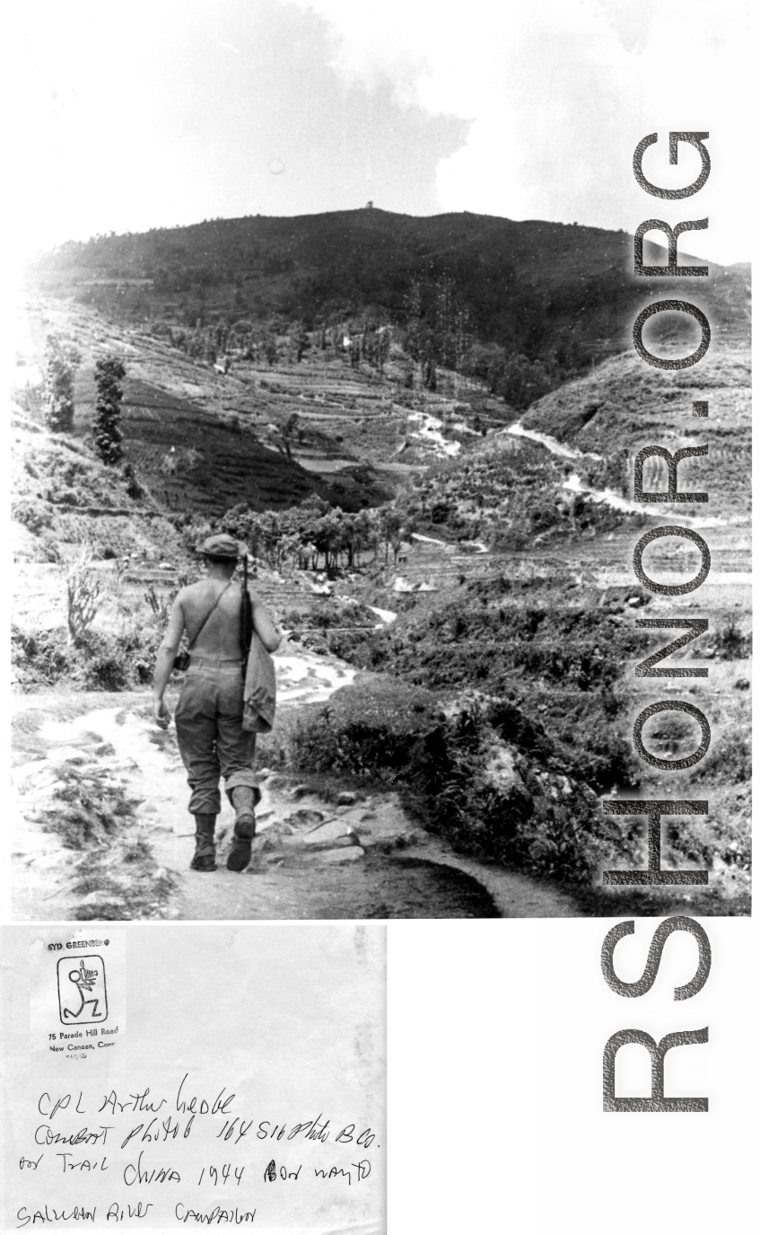 Cpl. Arthur Hedge, of 164th Signal Photographic Company, with carbine over shoulder, hikes trail towards Salween River campaign, 1944.