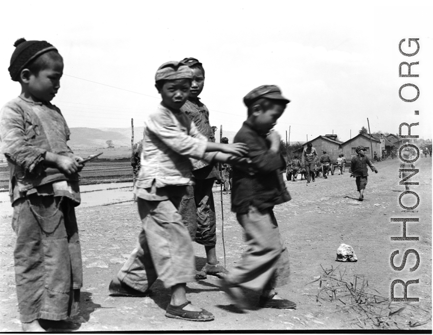 Local boys play beside road in China during WWII, in Yunnan province.