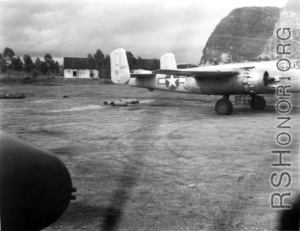 An 11th Bomb Squadron B-25J, #43-4387, in the preparation area at either Liuzhou or Guilin base, Guangxi province, China, in the fall of 1944. Photo was taken from the right side gunner position of another B-25. The propellers of '4387' are turning, so both aircraft are either returning from a mission or preparing to go on one.