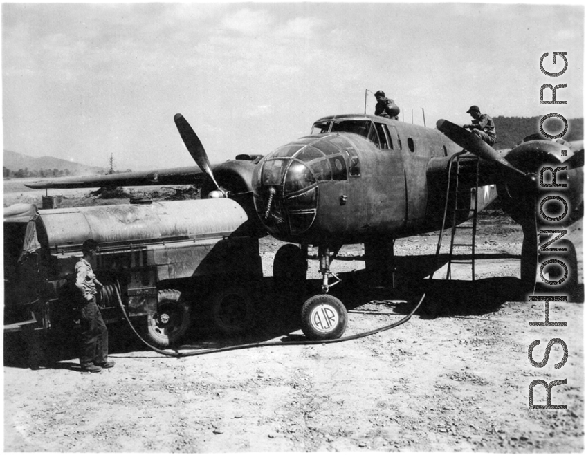 Men refueling a B-25 bomber in SW China. During WWII. The aircraft's wheel has been painted with "AJR" for Air Jungle Rescue.