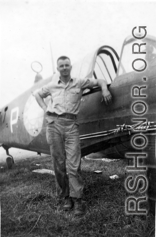 Elmer Bukey posing alongside a salvaged P-40 in the service area at Guilin. During WWII.