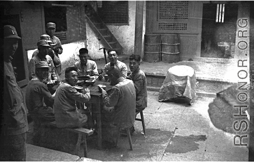 Chinese soldiers take a meal during WWII in the courtyard of a home, in Yunnan province, China, most likely around the Luliang air base area.