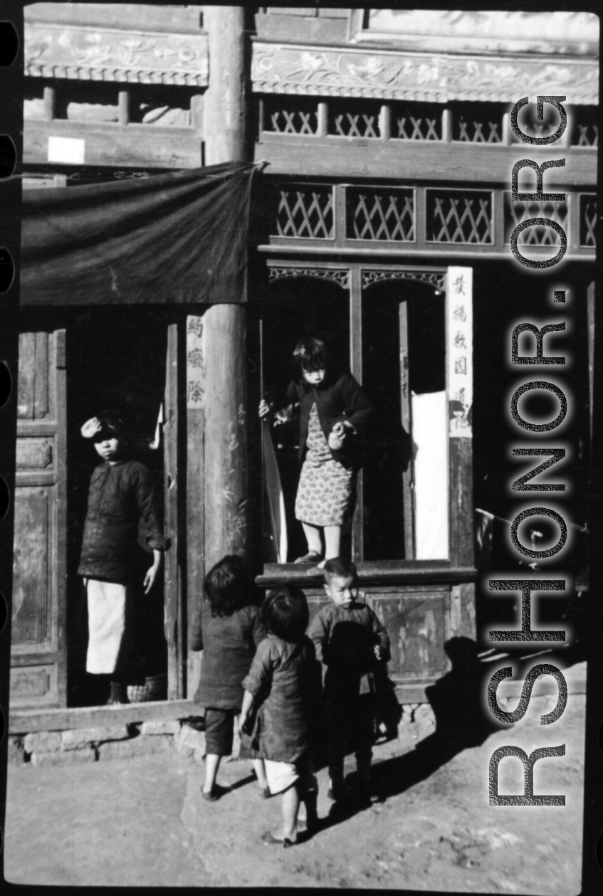 A kid in Guilin, China, climbs through shop window. During WWII.