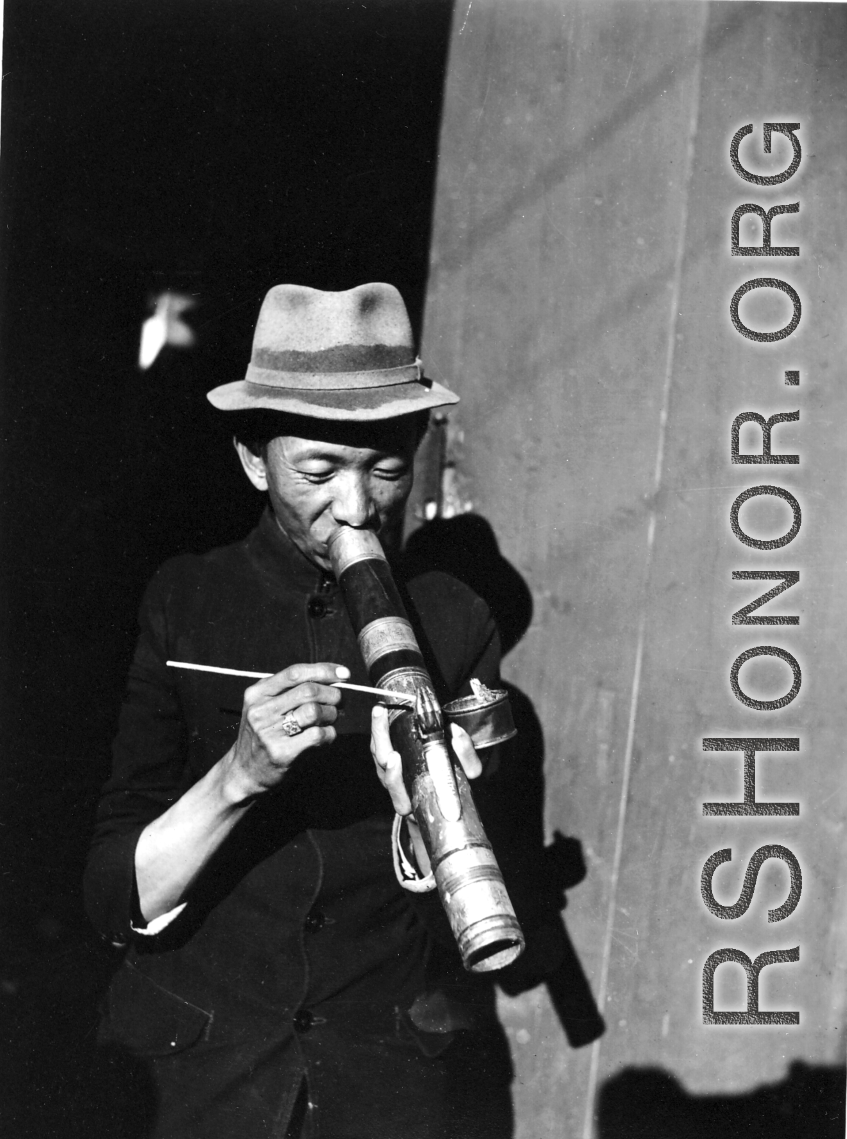 A Chinese man smokes from an elaborate decorated pipe in China during WWII.