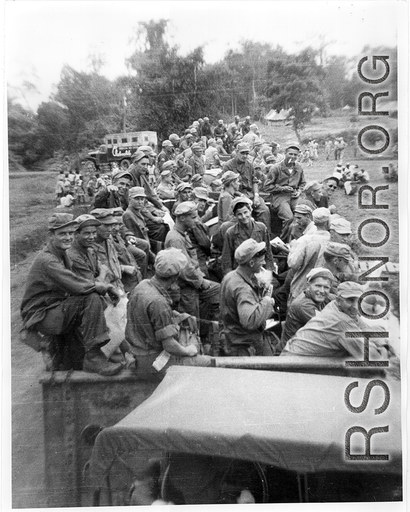7th Veterinary Company GIs packet tightly into train cars for transport. A Red Cross "Clubmobile" truck is parked on a road in the background. During WWII in the CBI.