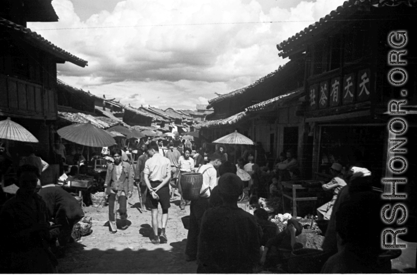 Local scenes and local people in Yunnan province, China, most likely around the Luliang air base area.  A local street in a village or town near the American air base. The sign on the building on the right advertises a tea house 天天有茶社.