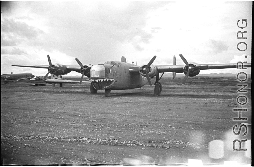 The Consolidated B-24 bomber "Nip Nipper," serial #42-72837. This is later in the war, and the B-24 has been modified to carry cargo, with the nose guns (and much more) removed. Note the aircraft wing on blocks to the left, and the salvaged C-47 fuselage in the background. During WWII, in China.