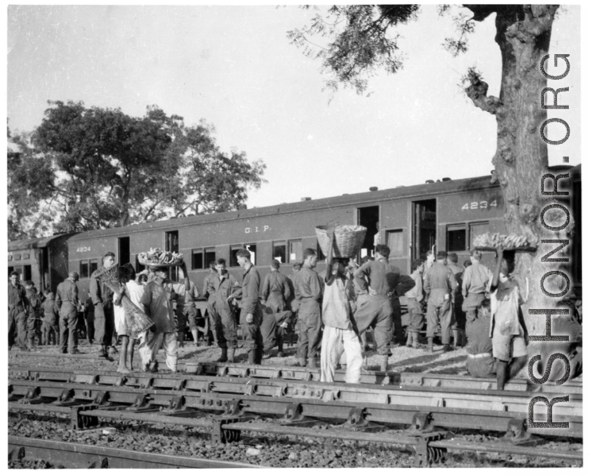 GIs and local vendor mingle during a rest stop on the train in India during WWII.