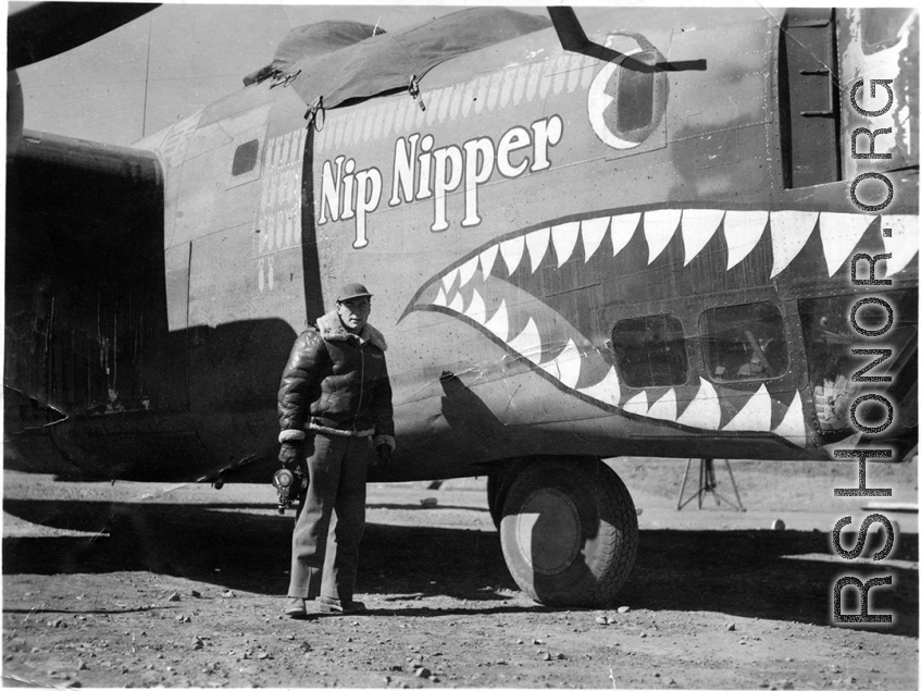 Selig Seidler, camera in hand, standing before the B-24 "Nip Nipper" somewhere in China during WWII.