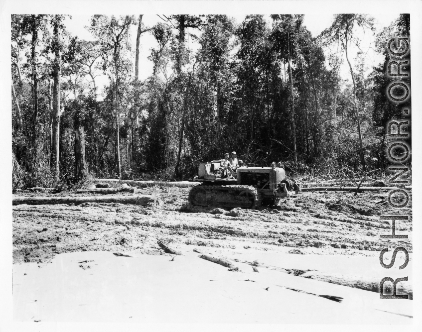 Bulldozer pulling log through mud in Burma.  797th Engineer Forestry Company in Burma.  During WWII.