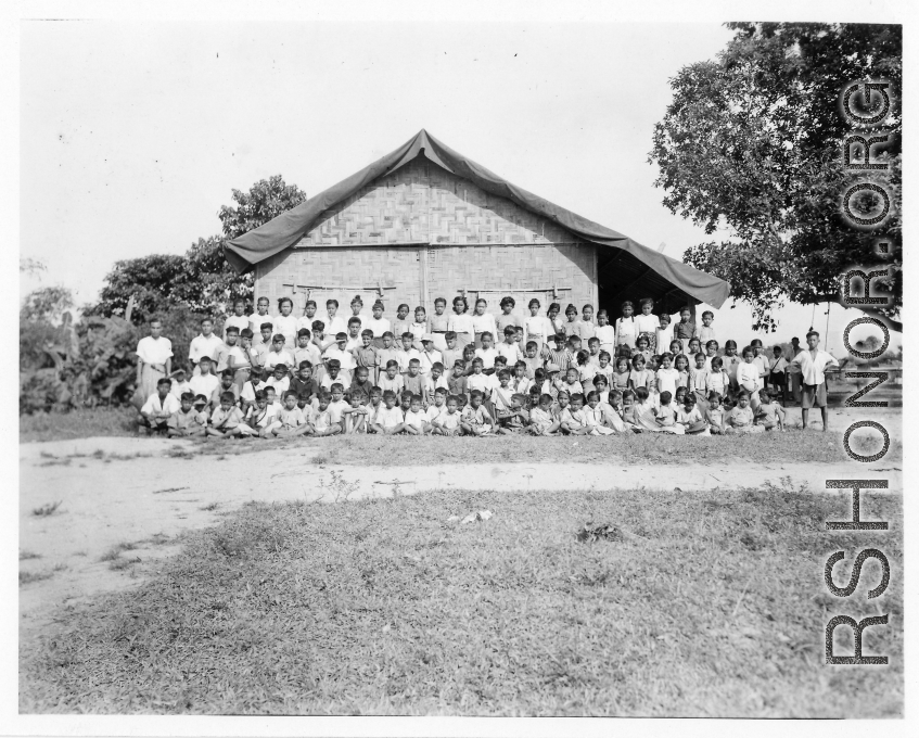 Local people in Burma near the 797th Engineer Forestry Company--A large group of children pose before a village school (most likely a missionary school) in Burma.  During WWII.