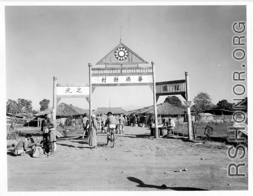 A Chinese settlement in Burma, with Nationalist insignia on gate archway. This is likely to be a settlement highly reliant on trade and commerce as its niche.  Near the 797th Engineer Forestry Company.  During WWII.  "华侨新村“  “祖国之光”