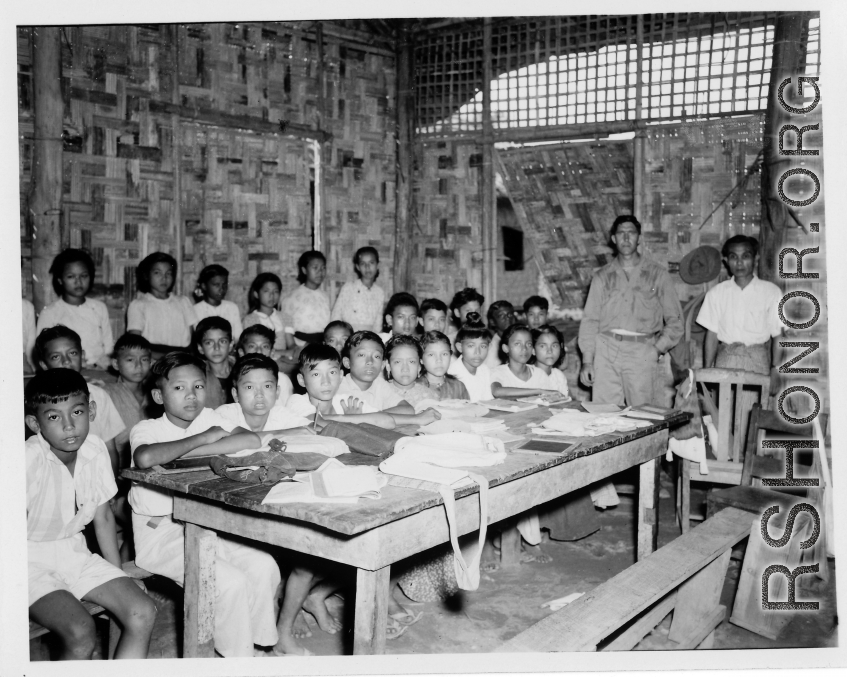 Local people in Burma near the 797th Engineer Forestry Company--GI visits a local school (very likely a missionary school, given the materials in the classroom and the clothing the kids are wearing) in Burma.  During WWII.