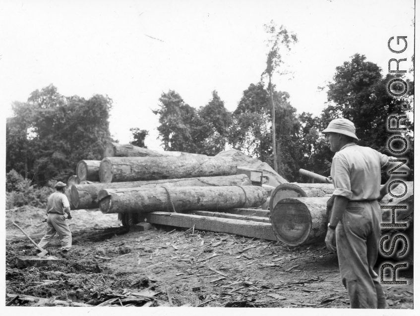 Wranging large logs of truck and towards saw with chains at a lumber mill of the 797th Engineer Forestry Company in Burma.  During WWII.