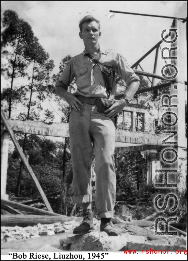 Bob Riese poses amongst remains of aircraft factory and hangers at the air base at Liuzhou, in 1945. The facilities at the base were first destroyed by the Chinese and Americans during retreat in the face of Ichigo during the fall of 1944, then may have been destroyed more by American bombardment during Japanese occupation, and possibly destroyed more by the Japanese as they retreated the area in 1945.
