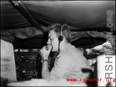A GI talks into a microphone of a portable radio in the back of a vehicle, during WWII in China.