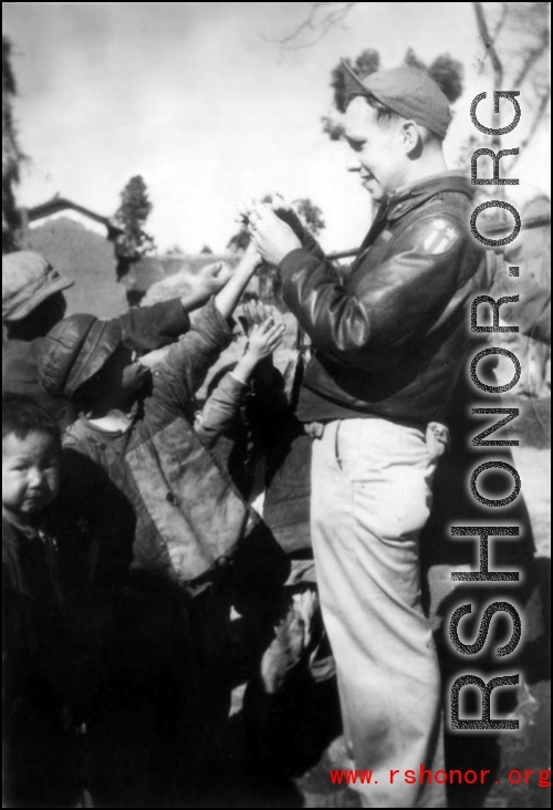Sgt. Robert H. Zolbe, with kids in China (almost certainly Yunnan Province), handing out candy. Zolbe served in the 308th Bombardment Group, 425th Squadron on a B-24 bomber.