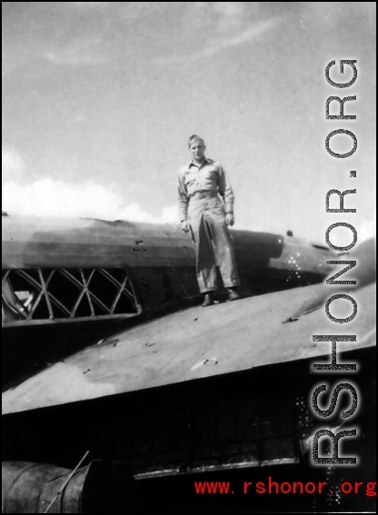 Paul Hunt standing of the wing of a damaged transport plane in the CBI.