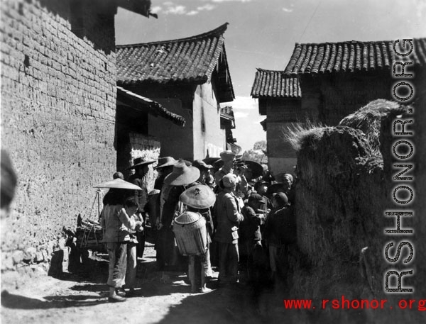 Villagers check out and American cameraman in a village in Yunnan province, China. During WWII.