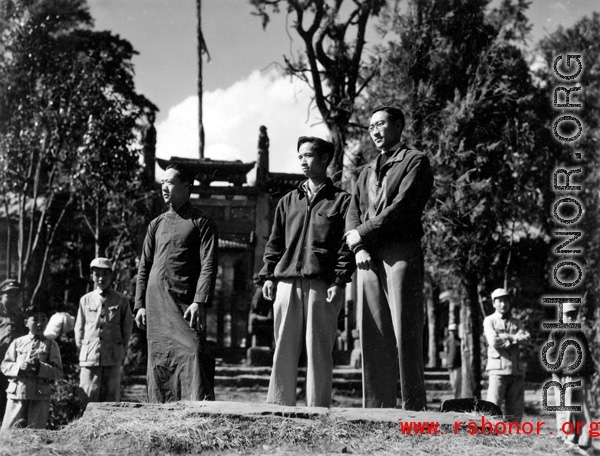 Local men stand on a small bridge in front of walled compound in Yunnan province, China. During WWII.