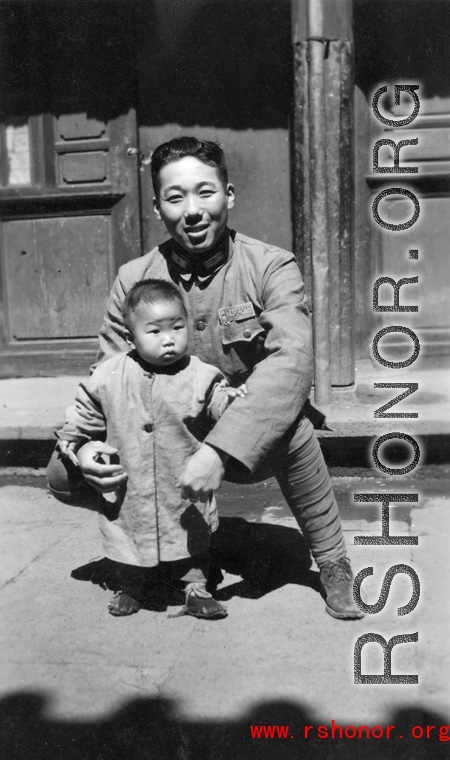 Local people in China during WWII: A Nationalist Chinese soldier holds a toddler during WWII.