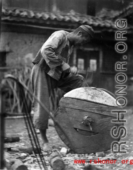 A craftsman repairing a wooden wheel in WWII China. 