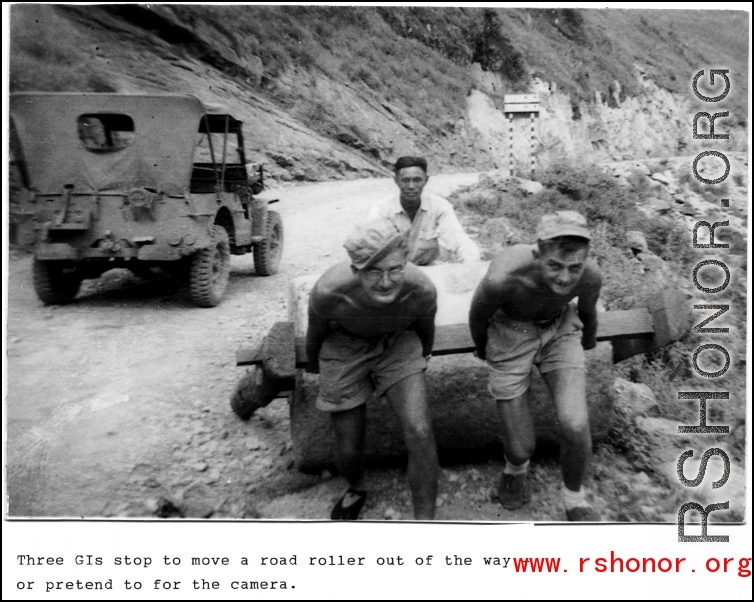 Three GIs stop to move roller out of the way... or pretend to for the camera. In the CBI during WWII.