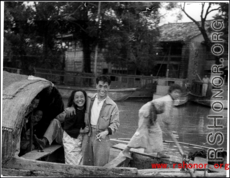 Young Chinese family in a boat travels by, during WWII.