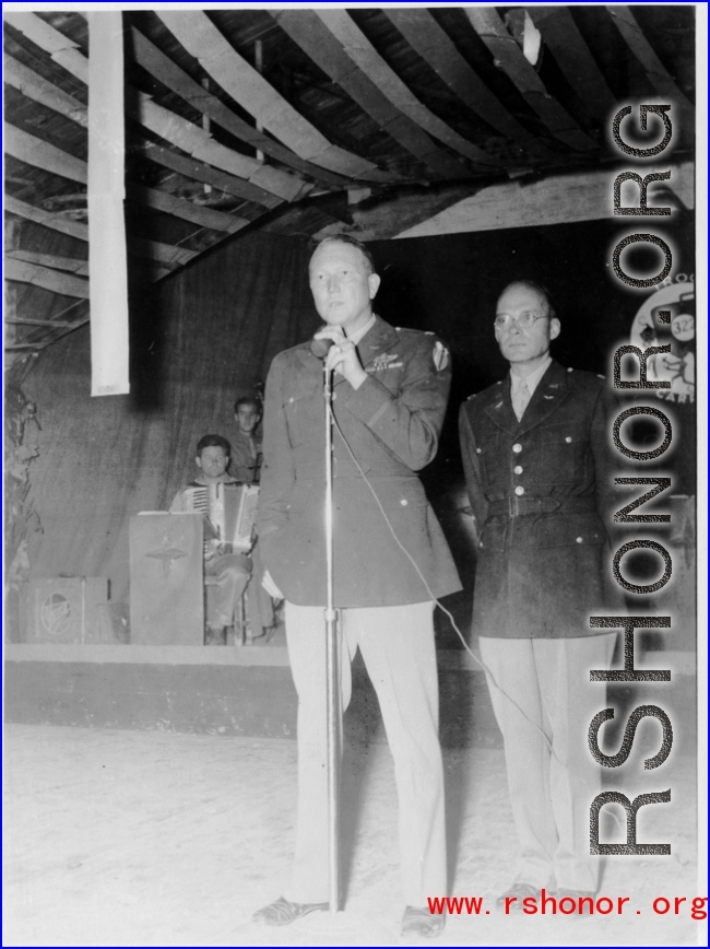 A GI holds the microphone as musicians wait, in the CBI during WWII. 322nd Troop Carrier.