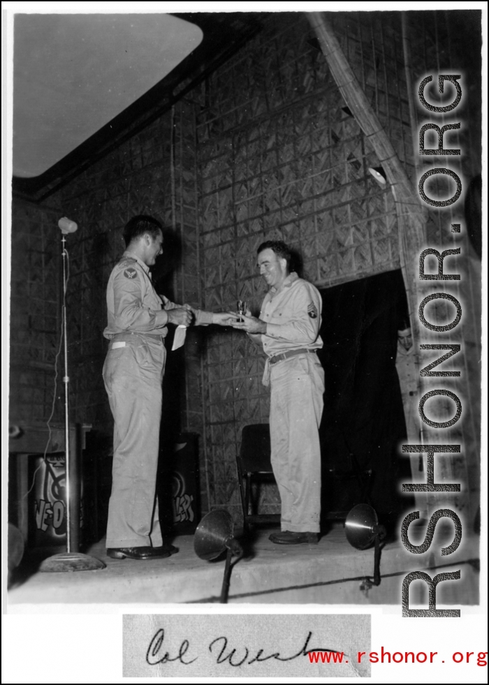 A GI wins a prize during a variety show, while the band Jive-o-Lieps waits to play music in the CBI during WWII. 54th Air Service Group.  Photo from Cal West.