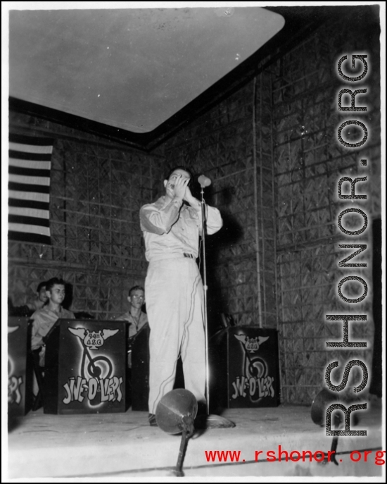 A GI plays harmonica as part of performance, while the band Jive-o-Lieps waits their turn. 54th Air Service Group.