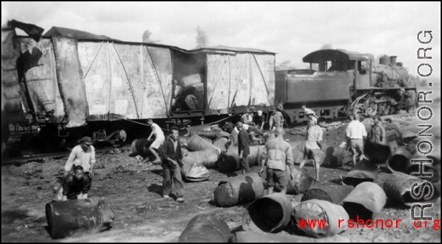 Chinese workers sorting through the aftermath of Japanese bombing raid on railway with load of fuel barrels. Liuzhou, China, September 1944.  From the collection of Frank Bates.