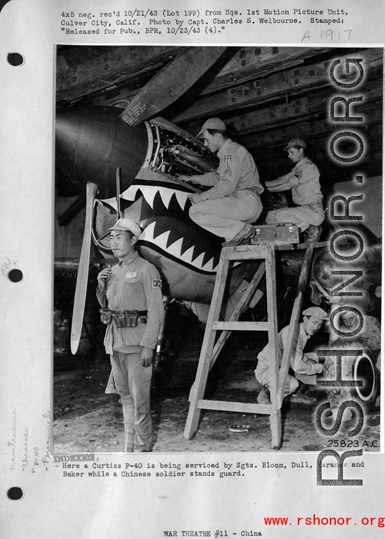 A Curtiss P-40 is being serviced by Sgts. Bloom, Dull, Yaranow, and Baker, while a Chinese soldier stands guard.