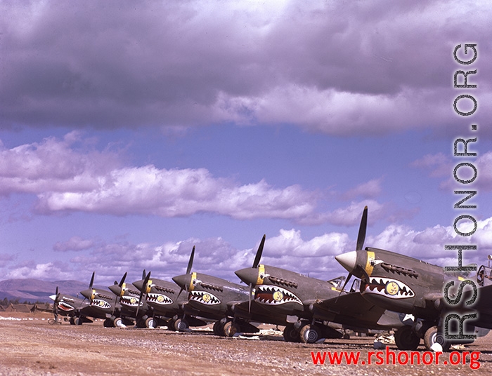 P-40Ks parked in a row in China during WWII, probably in Yunnan province, displaying the 26th Fighter Squadron "China Blitzers" badge on their sharkmouth.