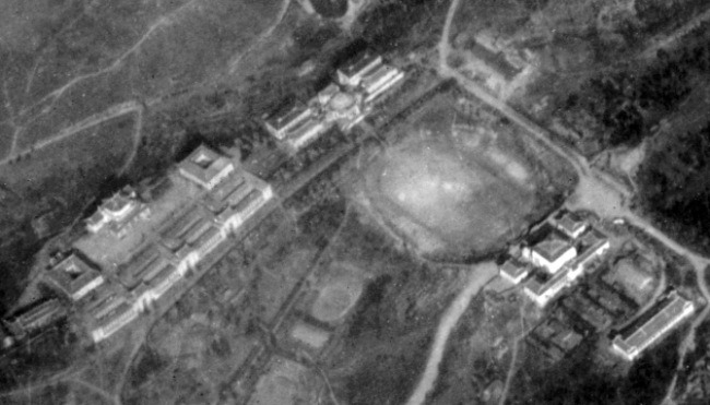 Aerial view of a large organized campus with large ornate buildings, an athletic track, housing, etc., in either SW China, Burma, or French Indochina, in the CBI, during WWII. Is this a university of some kind?
