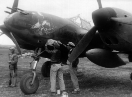 The P-38G Lightning fighter plane "Golden Eagle" (#42-13437 ) gets another bomb emblem after another mission, while Chinese guard keeps watch. #7871  Piloted by Capt Billie Beardsley.  This plane was a member of the 51st Fighter Group 449th Fighter Squadron "Twin Tailed Dragons"(thanks  jbarbaud).
