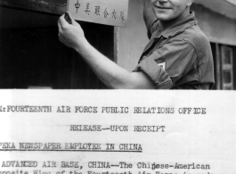 Leonard S. Jordan of the Chinese-American Composite Wing (CACW) hangs a sign indicating the "Photo Section," in both English and Chinese.  照相室，中美联合大队。