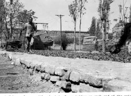 A farmer in northern China with baskets on a shoulder pole. Note the old town wall in the background.  Photo from Dorothy Yuen Leuba.
