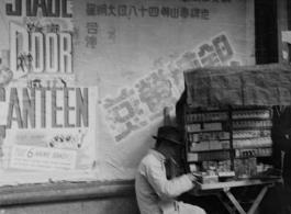 Cigarette vendor in China, set up in front of move advertisement for "Stage Door Canteen" (1943).  Photo from Jesse D. Newman.