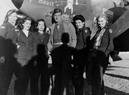 A US flyer surrounded by glamour gals stand in front of US war plane during WWII in the CBI. The plane appears to be a P-38 or F-5, with possible nickname "Sorry Beast."  Photo from Glenn W. Van Wynggarden.